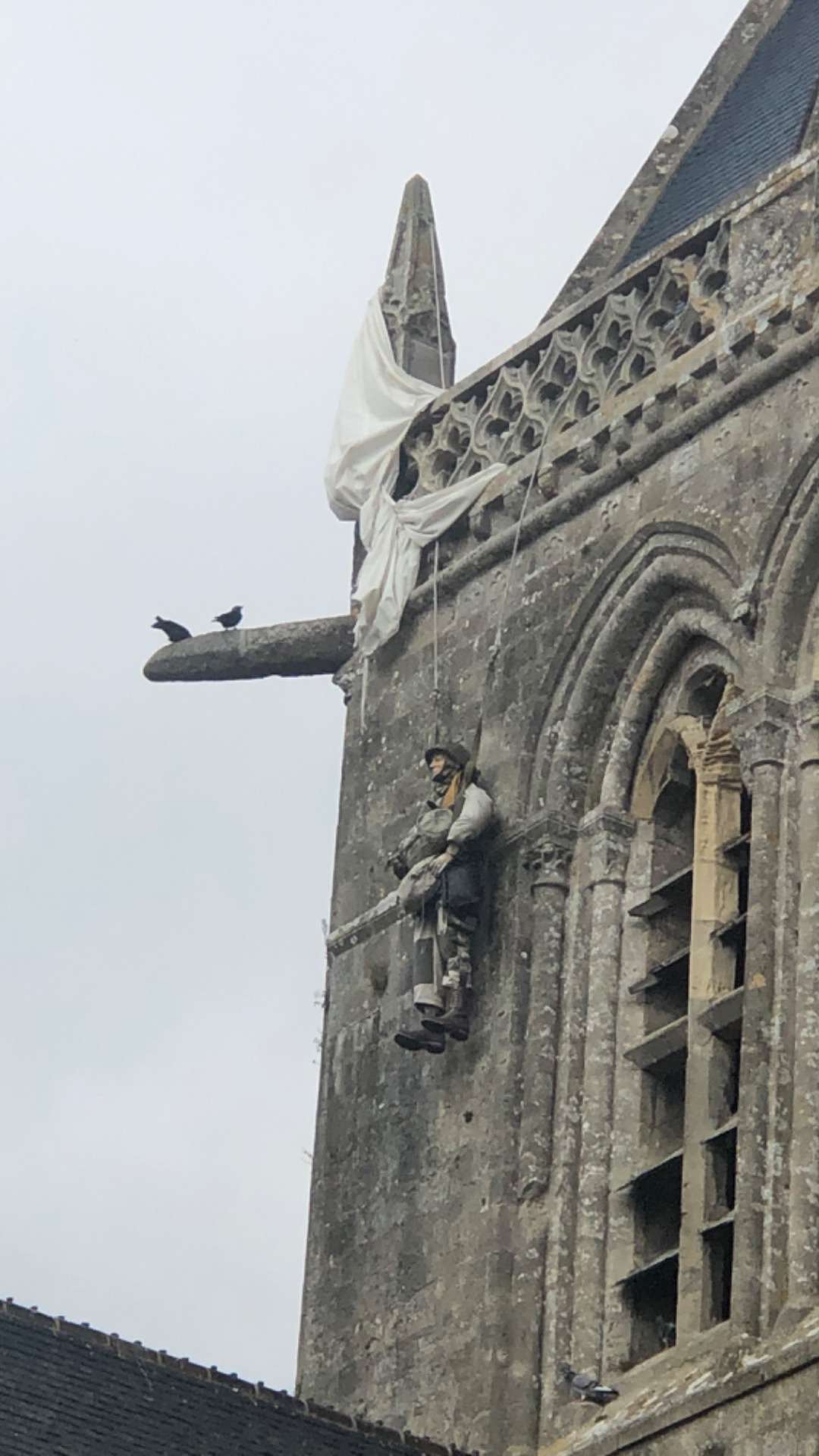 Statue of parachute caught on church with soldier handing from the chute